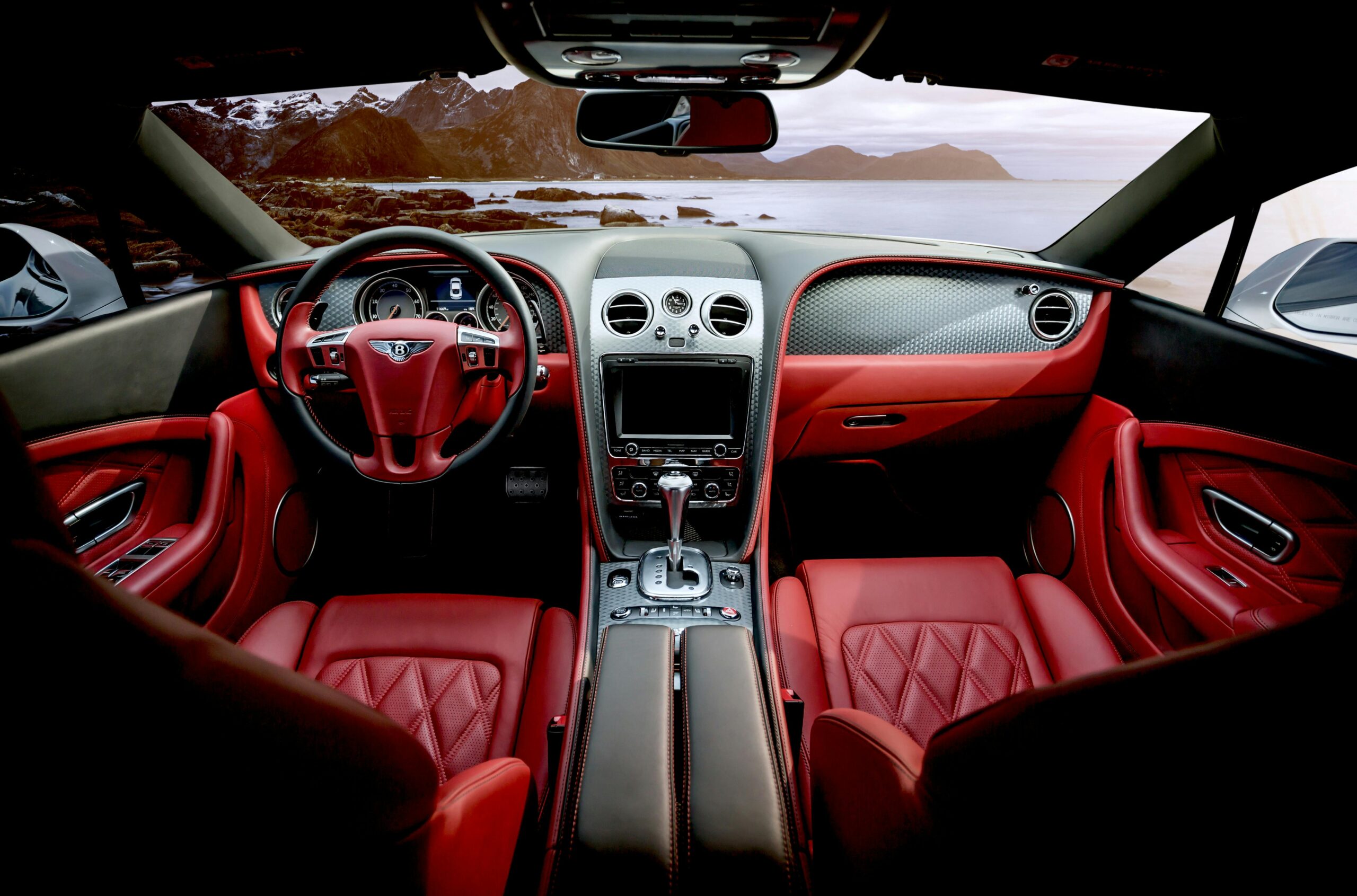 Red leather luxury sports car interior with mountain backdrop outside the window.